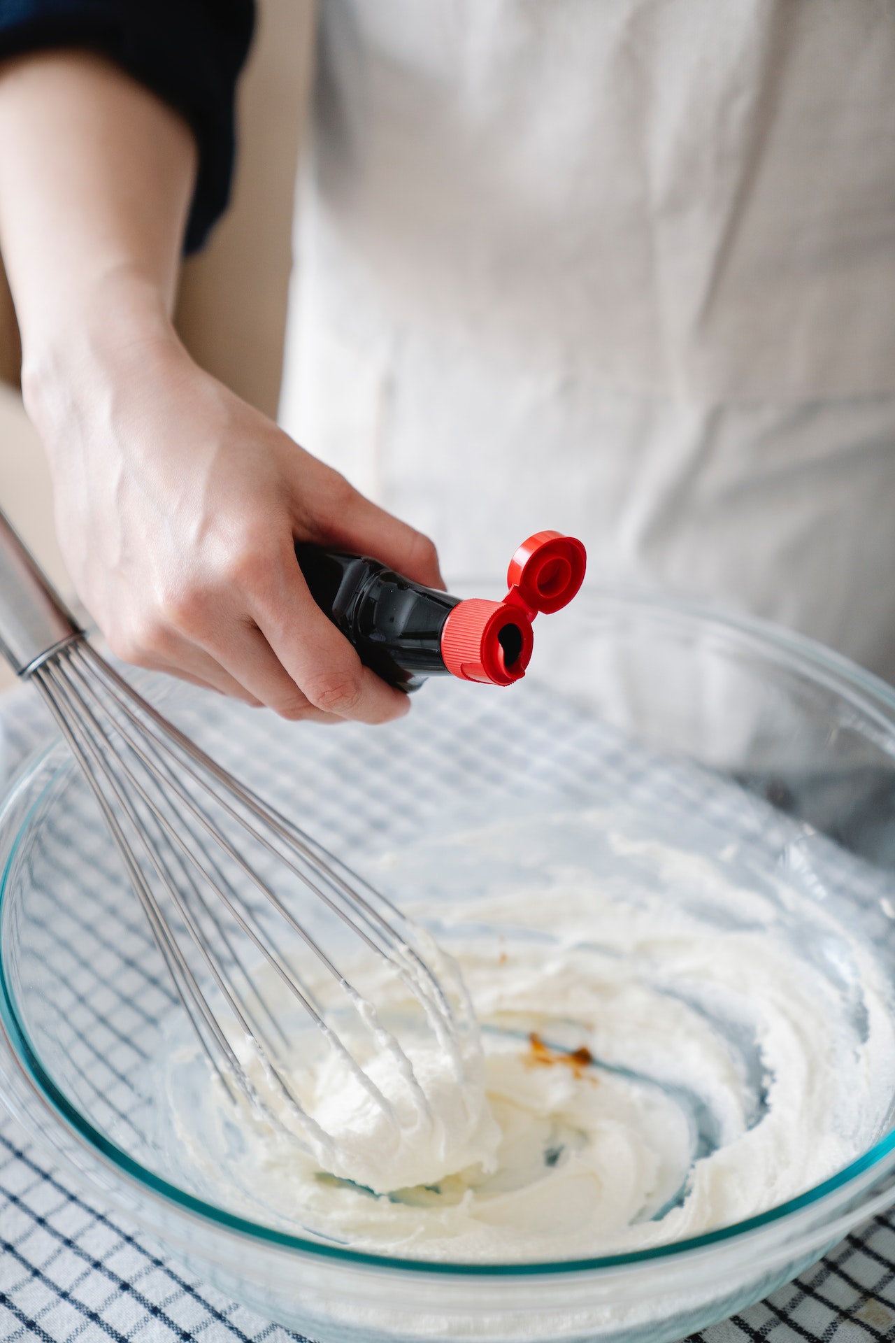 A woman adding vanilla extract to the cream