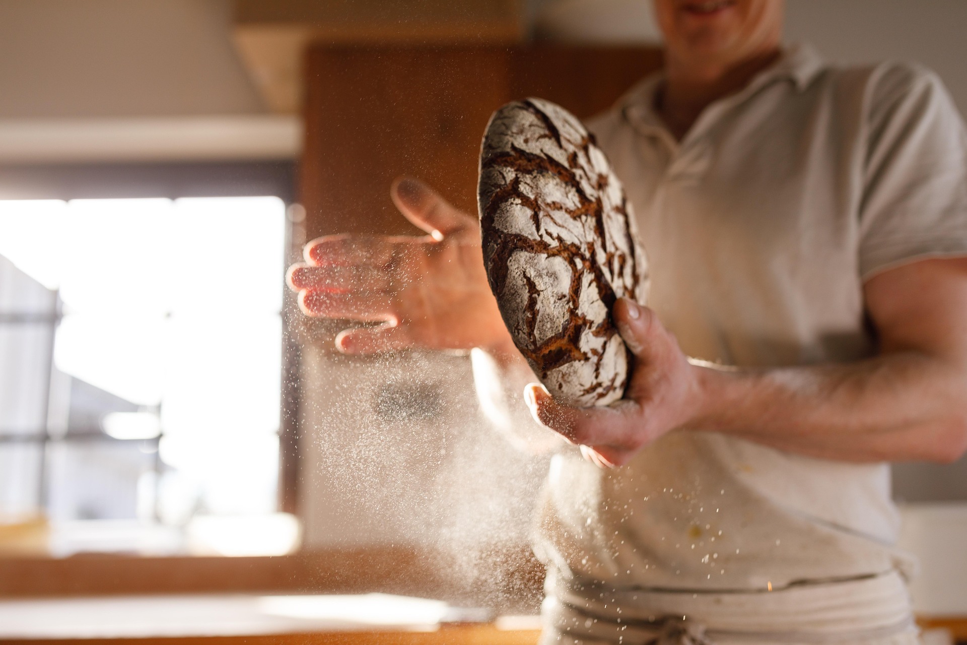 Baker adding a final coating to baked bread