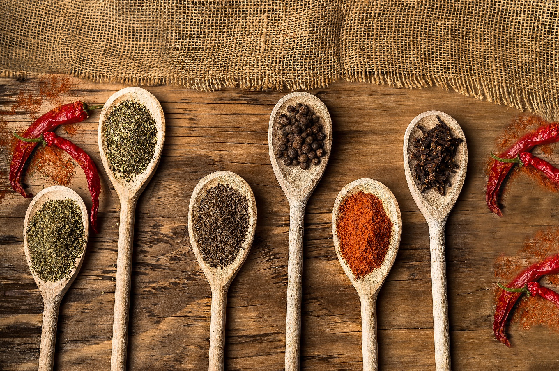 Six wooden spoons lined up on a table with different flavors displayed