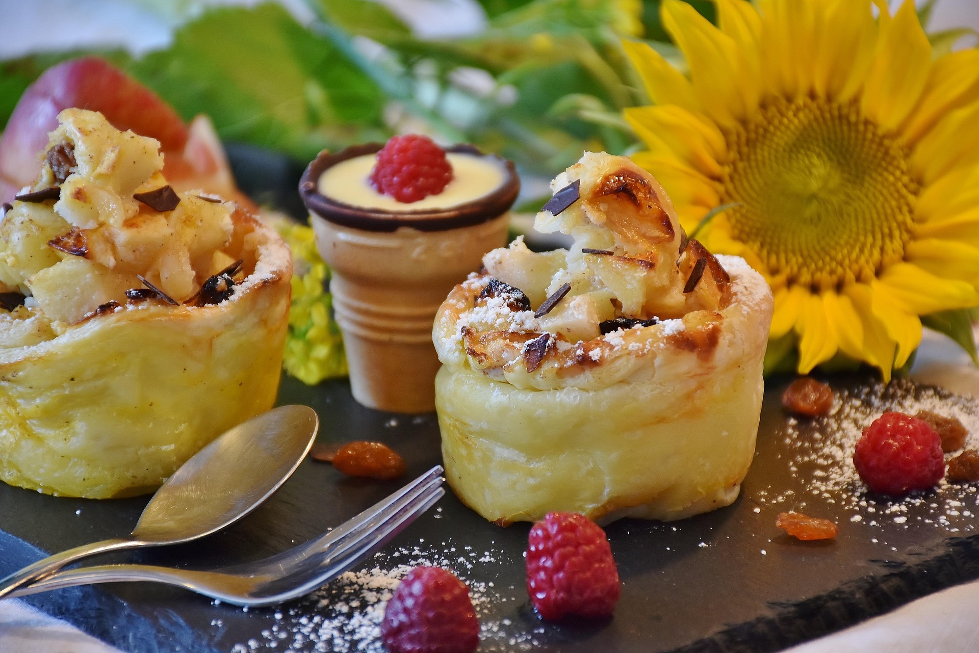 Photo of two apple desserts on a black slate board with confection sugar