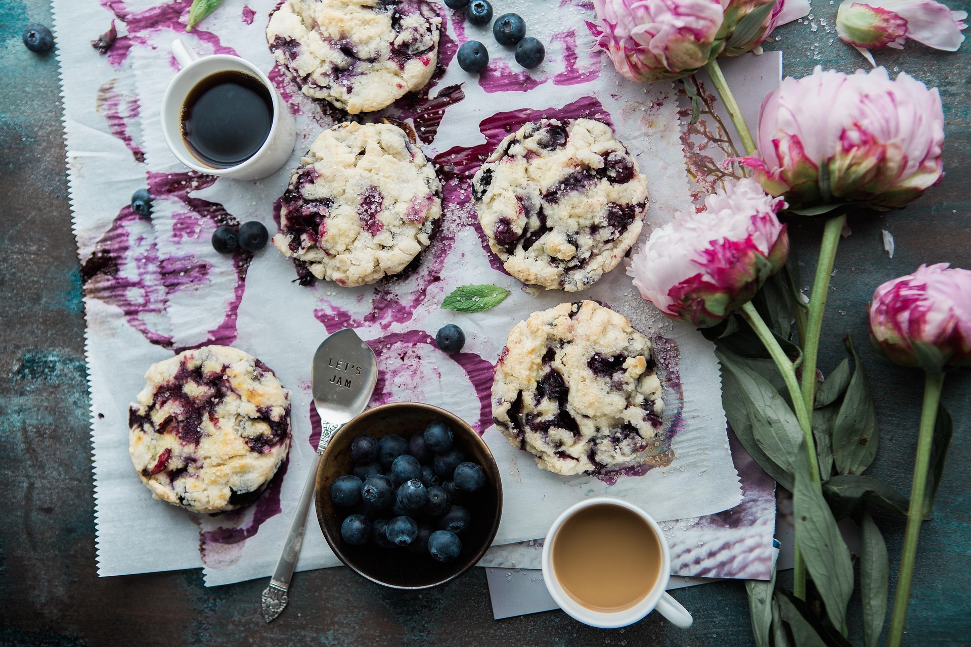 A selection of blueberry cookies made with natural ingredients and a cup of coffee beside them while they cool