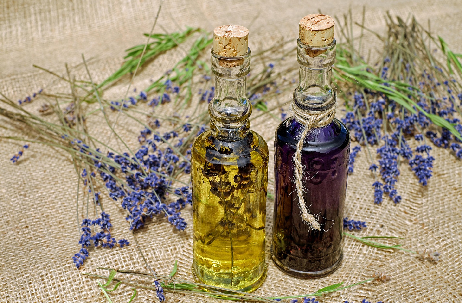 Lavender bottles surrounded by lavender cuttings on a hemp tablecloth