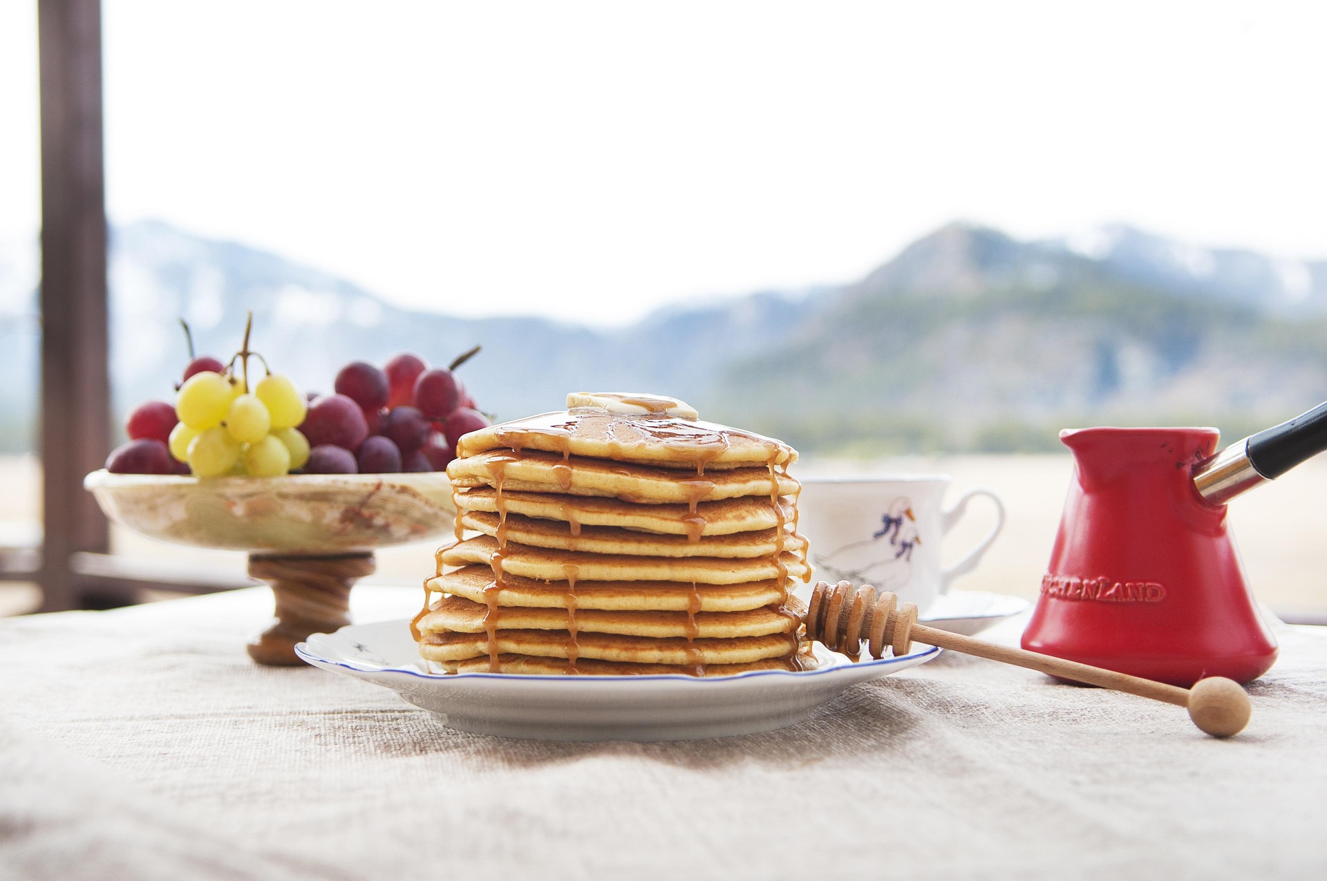 A stack of pancakes on a white dish with syrup drizzled on top